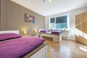 A modern bedroom with a bed, bedside tables, a window, and a radiator.