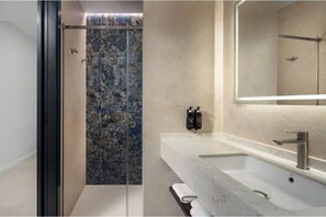 A modern bathroom with a glass shower enclosure, a marble sink, and a large mirror. - Vrbo Property (Estepona)