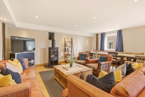 A cozy living room with a sofa set, a television, a fireplace, and a dining area. - Rose`s Bower Exclusive Hire - North East Escapes (Great Whittington)