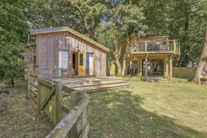 A rustic wooden cabin with a deck, surrounded by trees. - Rose`s Bower Exclusive Hire - North East Escapes (Great Whittington)