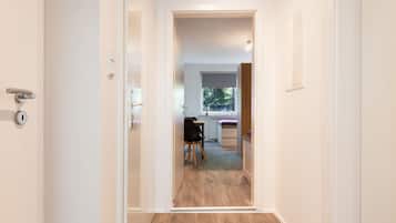 A hallway leading to a room with a window, a radiator, and a chair.