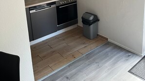Cozinha moderna com máquina de lavar louça, forno e relógio na parede.