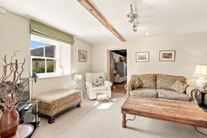A living room with a sofa, a chair, a coffee table, a television, and a window with a view. - The Old Woodworker’s Cottage - North East Escapes (Great Whittington)