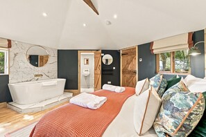 Ein modernes Schlafzimmer mit einem großen Bett, einer Badewanne und einer Holztür.