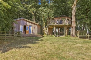 Ein rustikales Holzhaus mit Balkon und einem separaten Gebäude, umgeben von Bäumen.