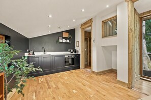 Eine moderne Küche mit dunklen Schränken, Holzboden und einem Fenster mit Blick auf eine natürliche Landschaft.