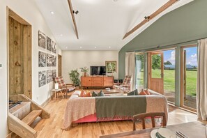Une pièce spacieuse comprenant un grand lit, une armoire en bois, un téléviseur et un coin repas avec une table et des chaises.