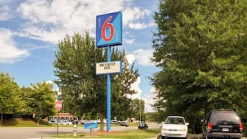 Segnaletica di motel con logo '6', un segnale di stop e un parcheggio con auto.