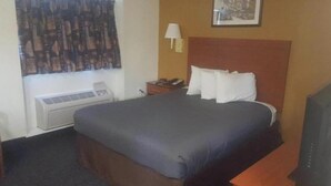 Een hotelkamer met een bed, een bureau, een lamp en een airconditioning.