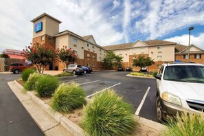 Un hotel con estacionamiento, varias edificaciones y cielo despejado.