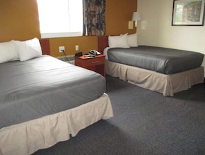 Una habitación de hotel con dos camas, un escritorio y un teléfono.