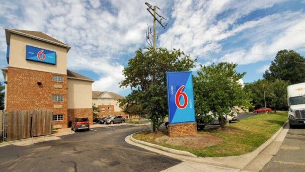 A motel with a prominent '6' sign, a brick building, and a parking area. - 1 Queen Bed|Smoking,Kitchen (Richmond VA)