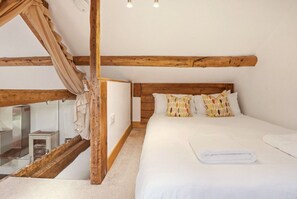 A bedroom with a wooden ceiling, a bed with white bedding, and a window with curtains. - The Hayloft - North East Escapes (Great Whittington)
