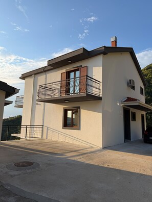 Un bâtiment à deux étages doté d’un balcon, d’un garage et d’un couvercle de regard d’égout.