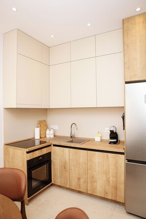 Une cuisine moderne avec des meubles en bois, un réfrigérateur en acier inoxydable, un four encastré et une machine à café.