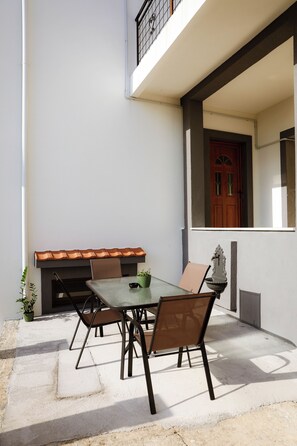 Eine Terrasse im Freien mit Tisch und Stühlen, einem kleinen Topfpflanzen und einem Ziegeldach.