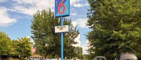 A motel sign with a '6' logo, a stop sign, and a parking lot with cars.