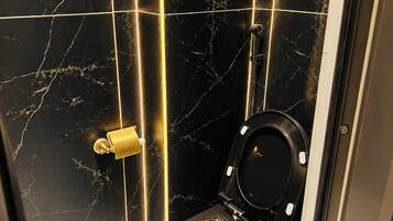 A bathroom with a black toilet, marble walls, and a patterned floor.