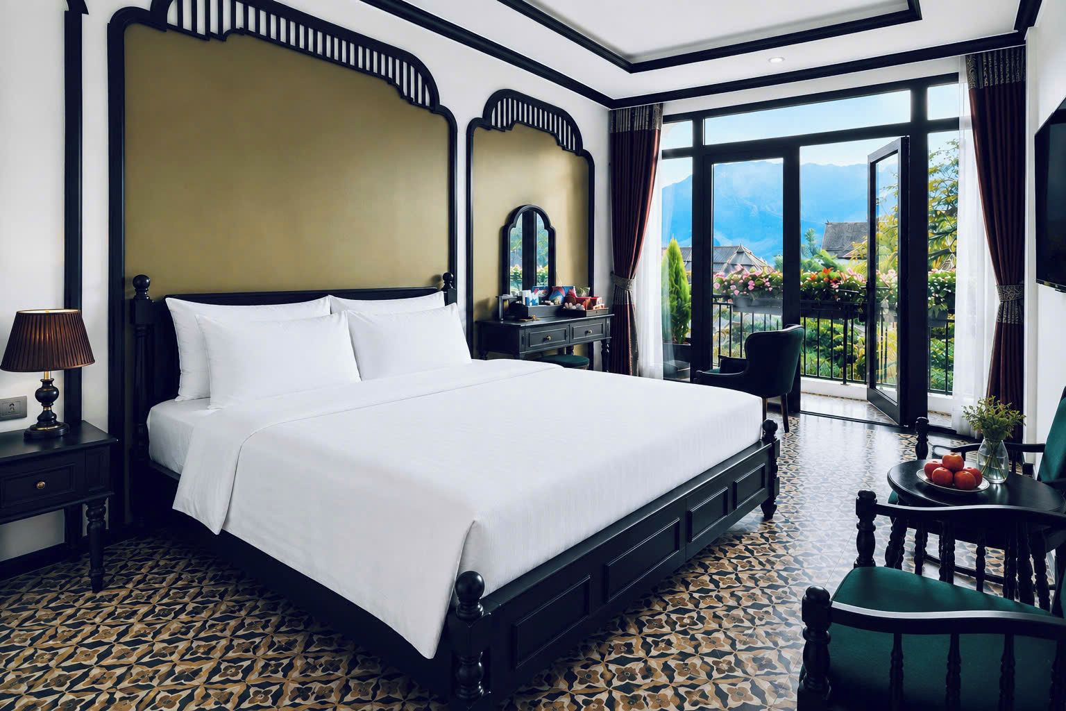 A hotel room with a large bed, a nightstand, a desk, a chair, and a view of the outdoors.