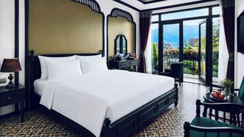 A hotel room with a large bed, a nightstand, a desk, a chair, and a view of the outdoors.