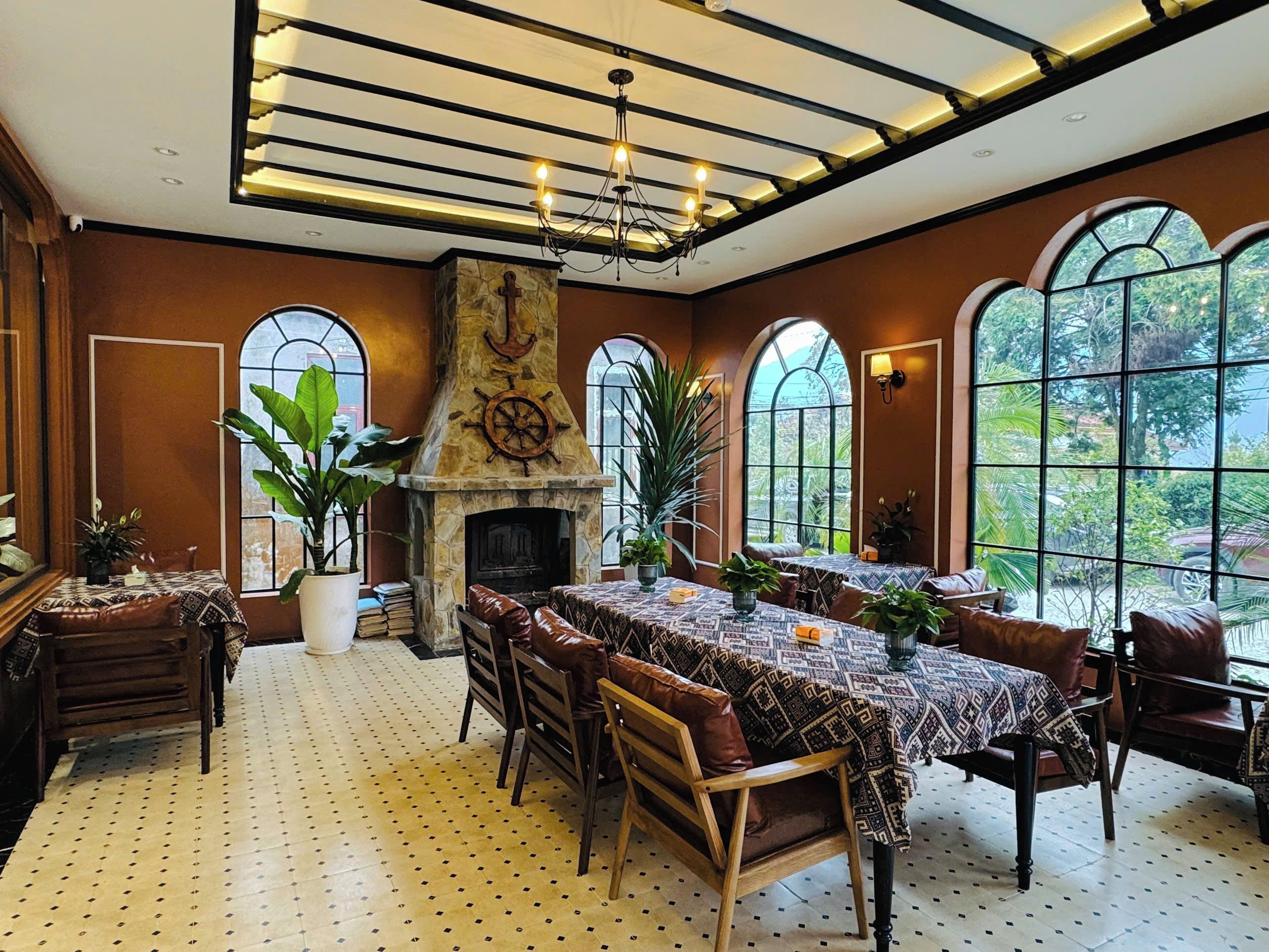 Un comedor con chimenea, ventanas amplias y techo con vigas a la vista.