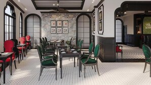 A dining area with a ceiling fan, stone wall, framed artwork, and a mix of red and green upholstered chairs. - D'Mont Boutique Hotel & Coffee (Sa Pa)