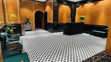 Un vestíbulo con piso estampado, zona de estar, mostrador de recepción y una escalera.
