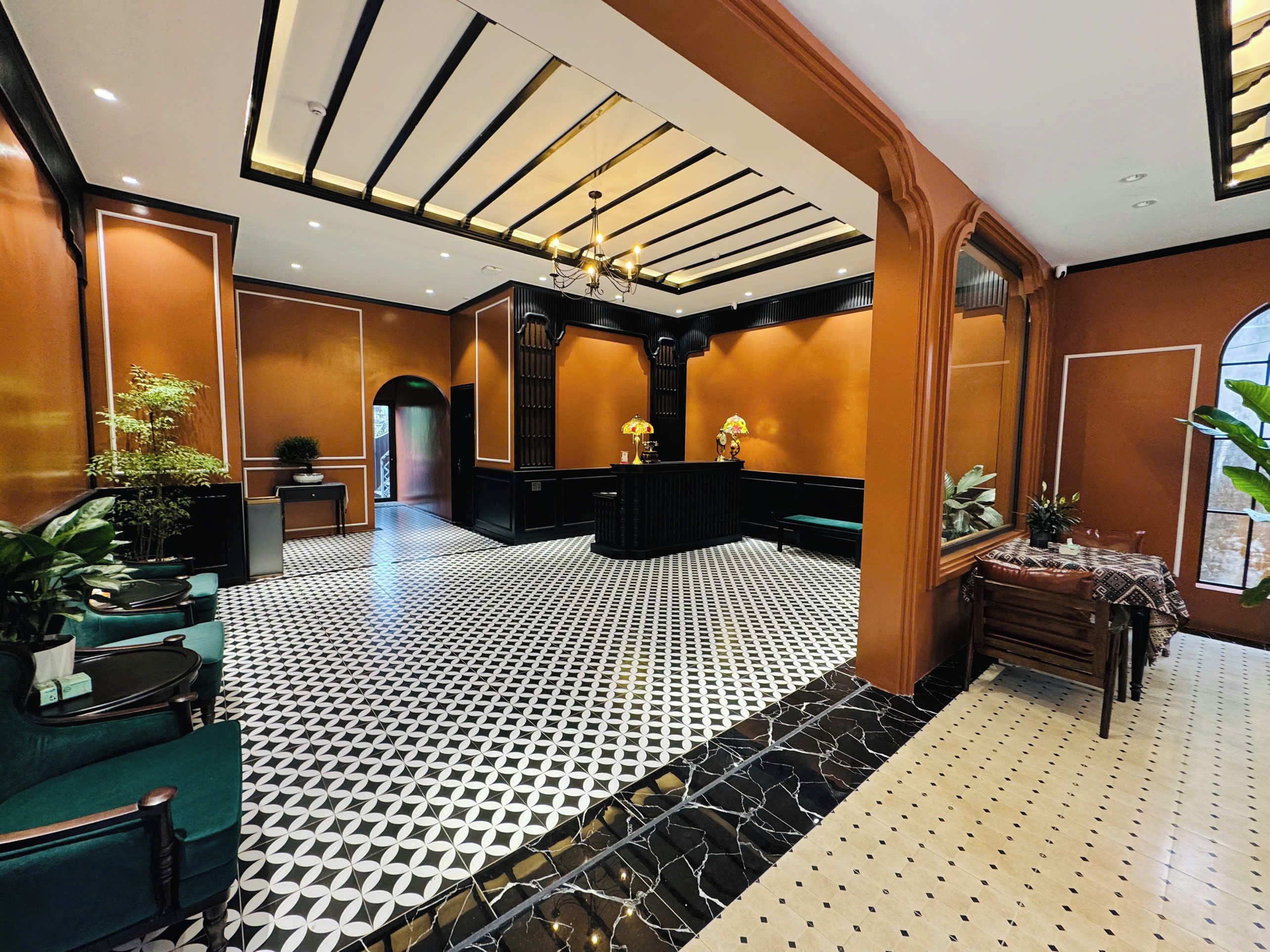 A hotel lobby with a check-in counter, seating area, and a patterned floor.