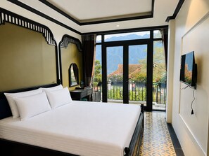 Une chambre d’hôtel avec un grand lit, un téléviseur fixé au mur et un balcon offrant une vue sur les montagnes.