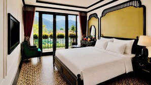 A hotel room with a large bed, a television, a desk with a lamp, and a view of a garden through a sliding door. - D'Mont Boutique Hotel & Coffee (Sa Pa)