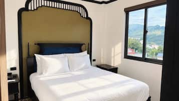 A hotel room with a bed, a nightstand, a window with a view, and a patterned floor.