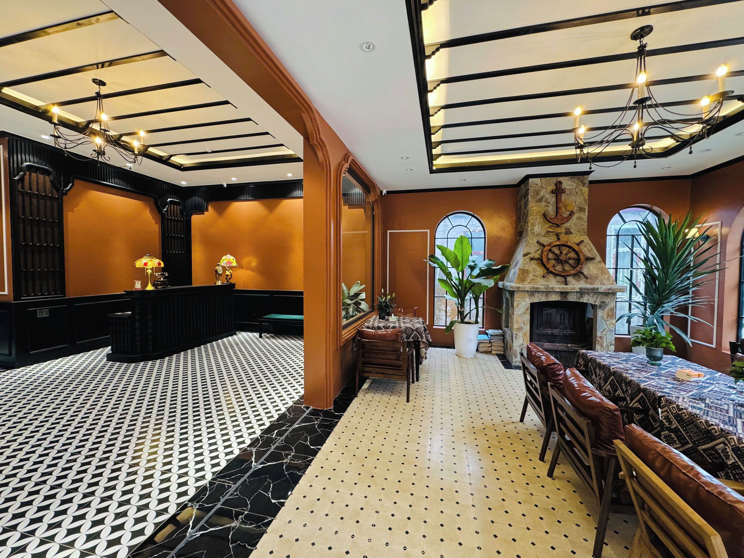Un hall de hotel con mostrador de recepción, zona de estar, chimenea y piso con diseño.