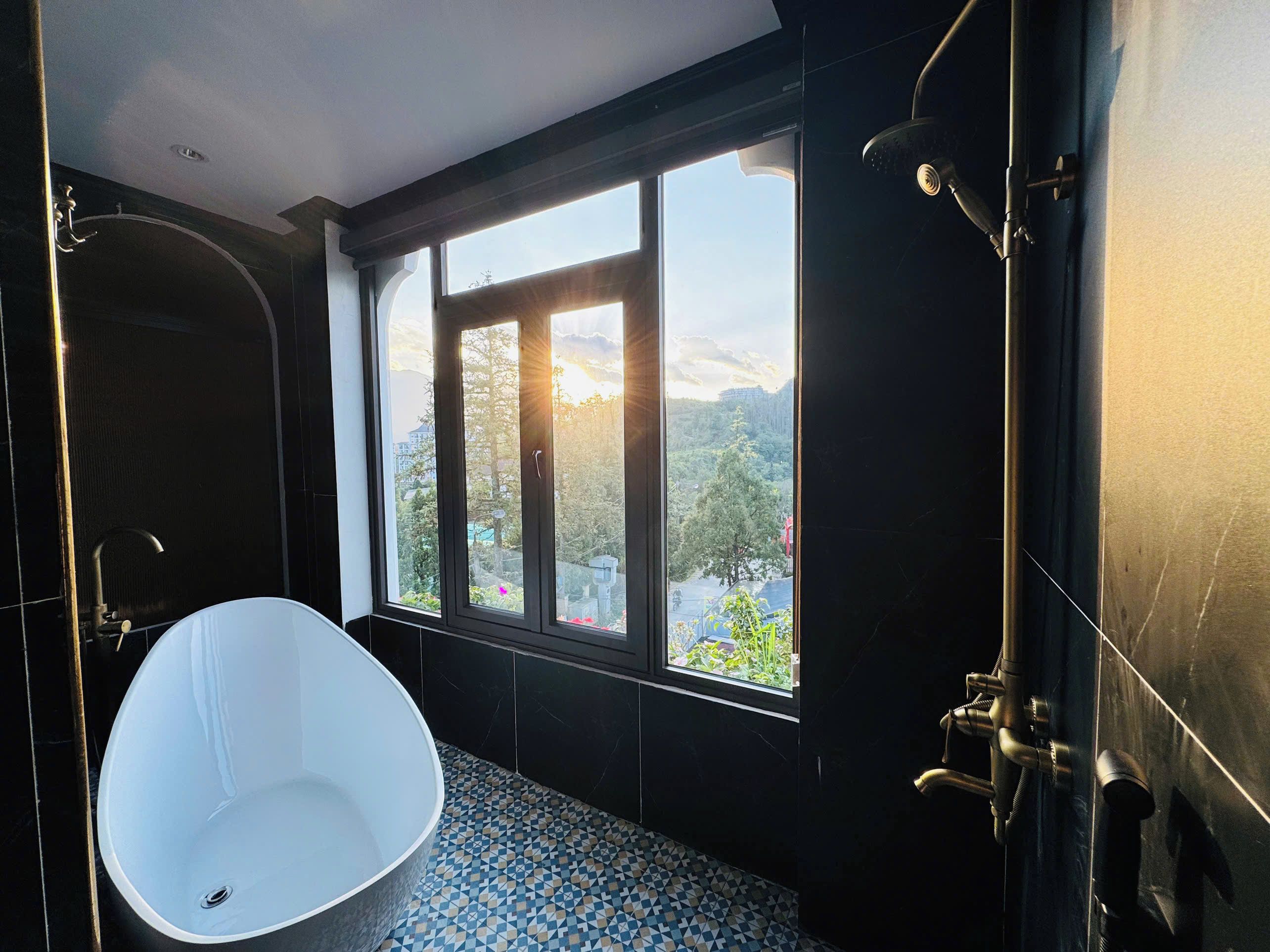 A modern bathroom with a freestanding bathtub, a large window with a view of a mountainous landscape, and a shower area.