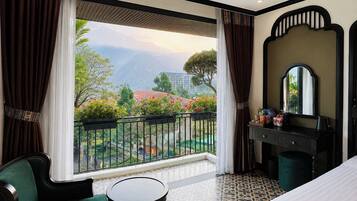 A hotel room with a balcony, a bed, a desk, and a chair.