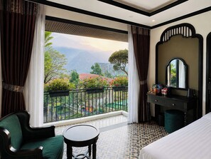 A hotel room with a balcony, a bed, a desk, and a chair.