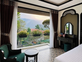 Una habitación de hotel con balcón, una cama, un escritorio y una silla.