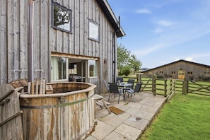 Ein rustikales Holzhaus mit Whirlpool, Sitzgelegenheiten im Freien und einem eingezäunten Hof.