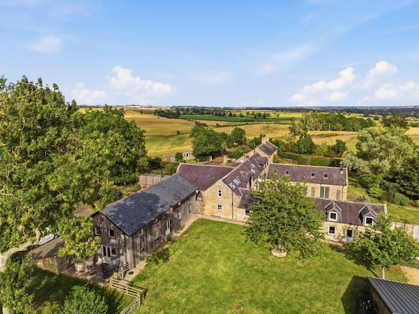 Ein großes, rustikales Bauernhaus mit mehreren Zimmern, umgeben von üppigem Grün und weitläufigen Feldern.