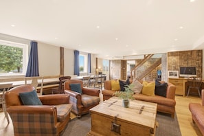 Ein geräumiges Wohnzimmer mit Ledersofas, einem Holztisch und einer Treppe zu einer weiteren Ebene.