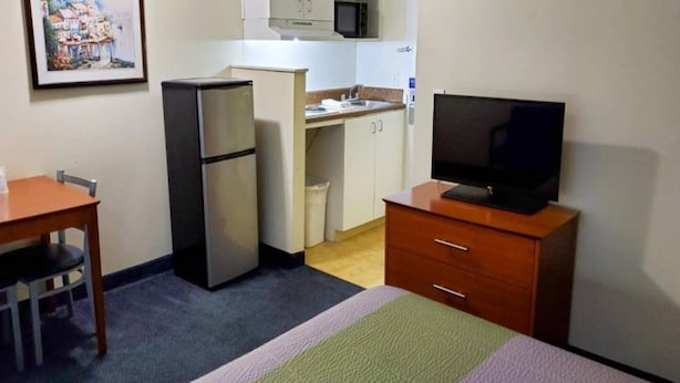 A compact hotel room with a bed, a small desk, a television, a refrigerator, and a kitchenette. - 2 Full Beds | Non-Smoking (Richmond VA)