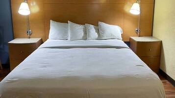 A hotel room with a large bed, two bedside tables, and two wall-mounted lamps.