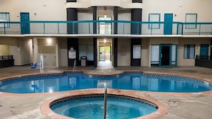 An indoor swimming pool with a hot tub in the center, surrounded by a concrete deck. - Cozy 2-Bed Queen|Pool|Free Wifi (Savannah GA)