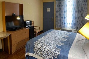 Una habitación de hotel con cama, televisor, escritorio, silla y puerta.