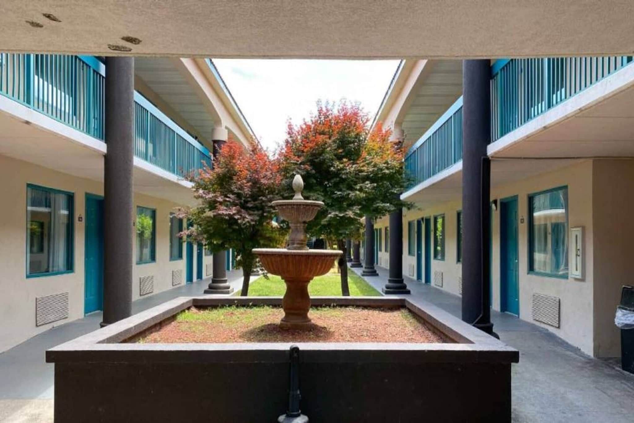 Un patio central con una fuente, rodeado por un edificio con varios balcones y ventanas.