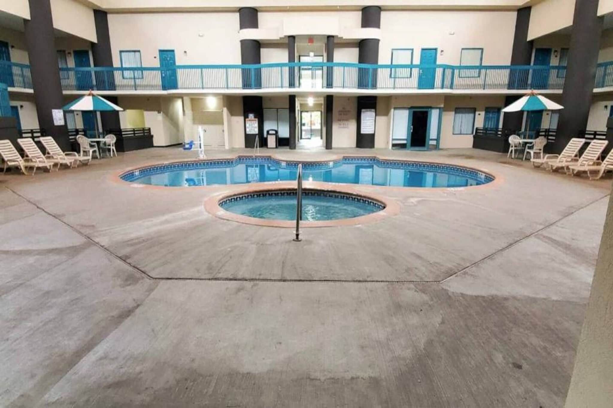 Un hotel con zona de piscina central, varios balcones y sillones de descanso.
