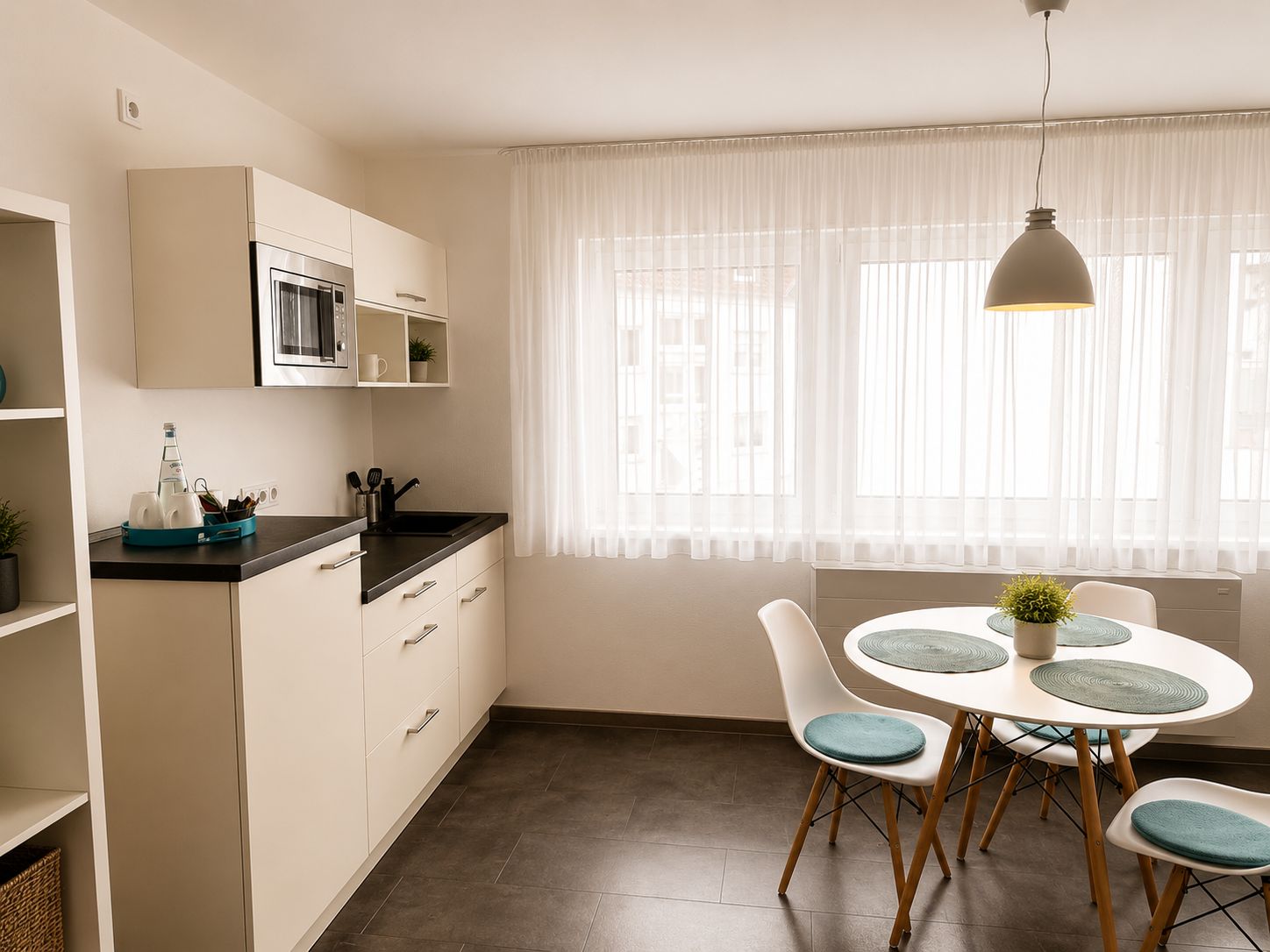 A modern kitchen with a dining area, featuring a microwave, cabinets, and a table with chairs.