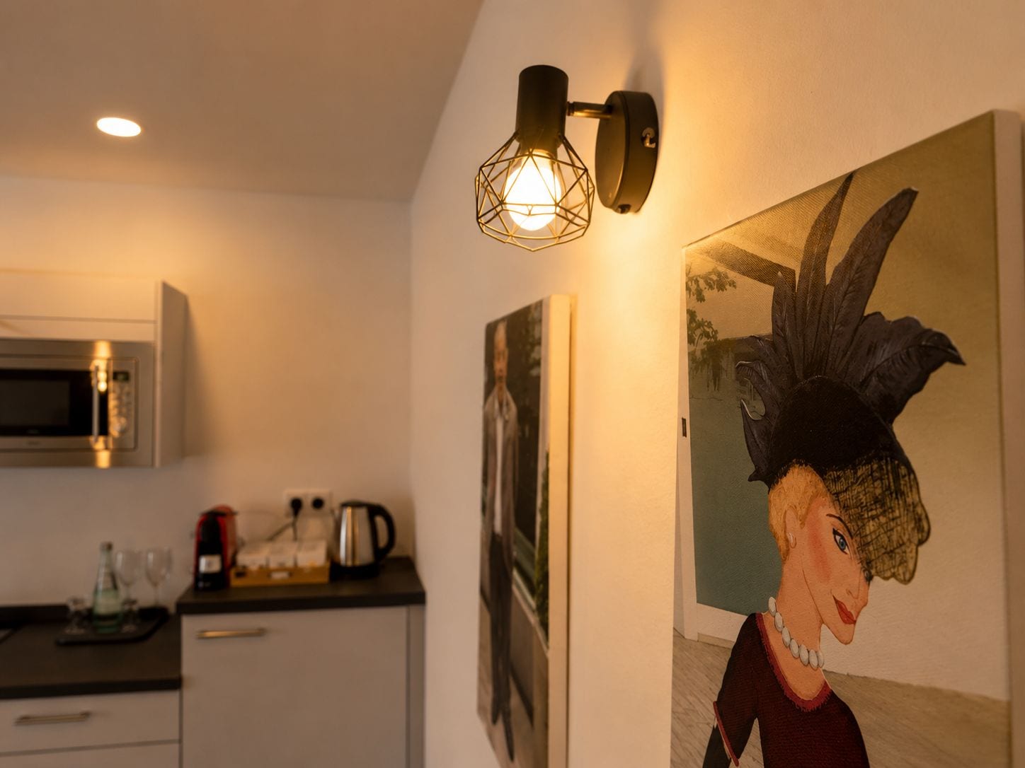 Eine Küche mit Mikrowelle, Kaffeemaschine und einem Bild einer Frau an der Wand.