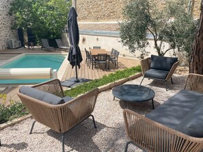A poolside area with wicker furniture, a table, and a covered umbrella. - The Domaine de la Feuilleraie (Montséret)