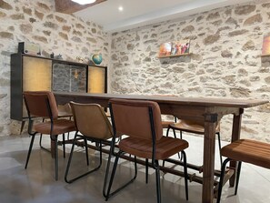 A dining area with a stone wall, a wooden table, and four chairs. - The Domaine de la Feuilleraie (Montséret)