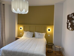 Ein Hotelzimmer mit einem Bett, Nachttischlampen, einem kleinen Tisch und einer Wanddekoration.